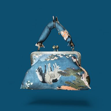 Cuento ilustrado Monedero de tela con estampado colorido y asas de tela. Fondo azul.