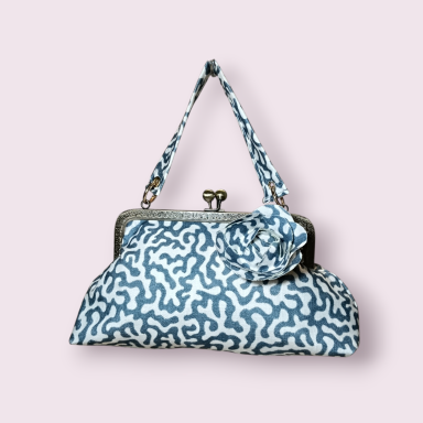 Azul de época Bolso de mano con diseño azul sobre fondo blanco y cierre metálico.
